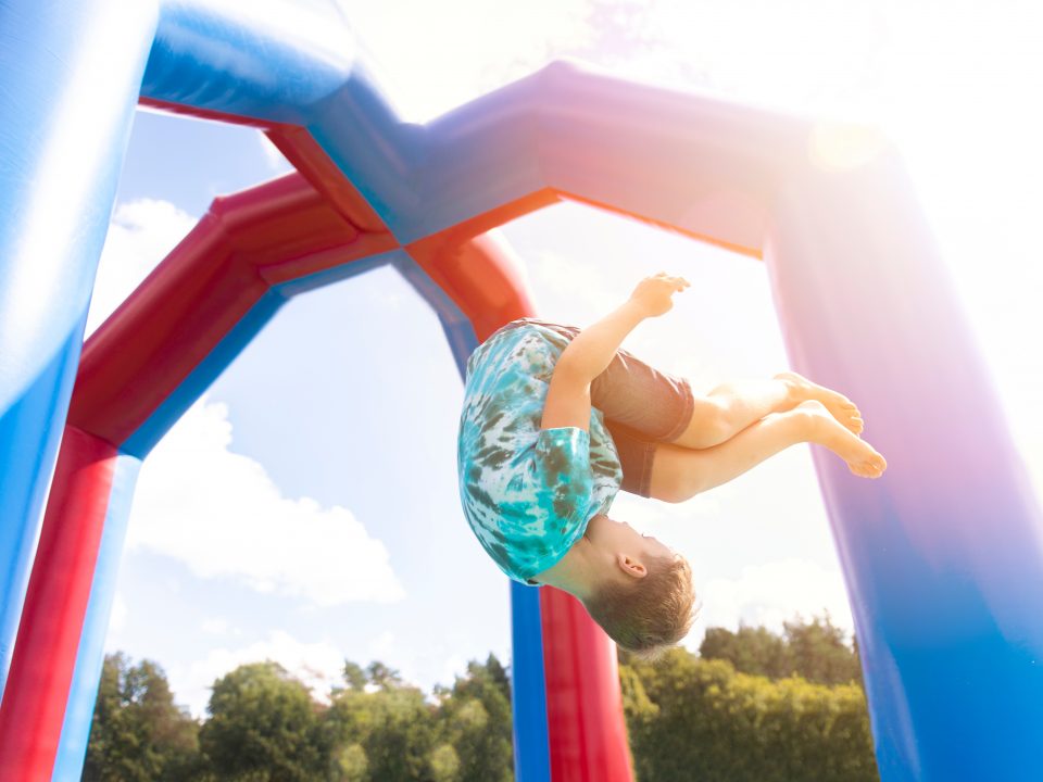 The joyful world of jumping castles. Why renting an inflatable for your event is a great idea.. In an inflatable jumping castle, a young boy is seen inverted.