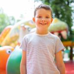 Why renting an inflatable for your event is a great idea. A juvenile male stands before a playground, gazing ahead with a curious expression.