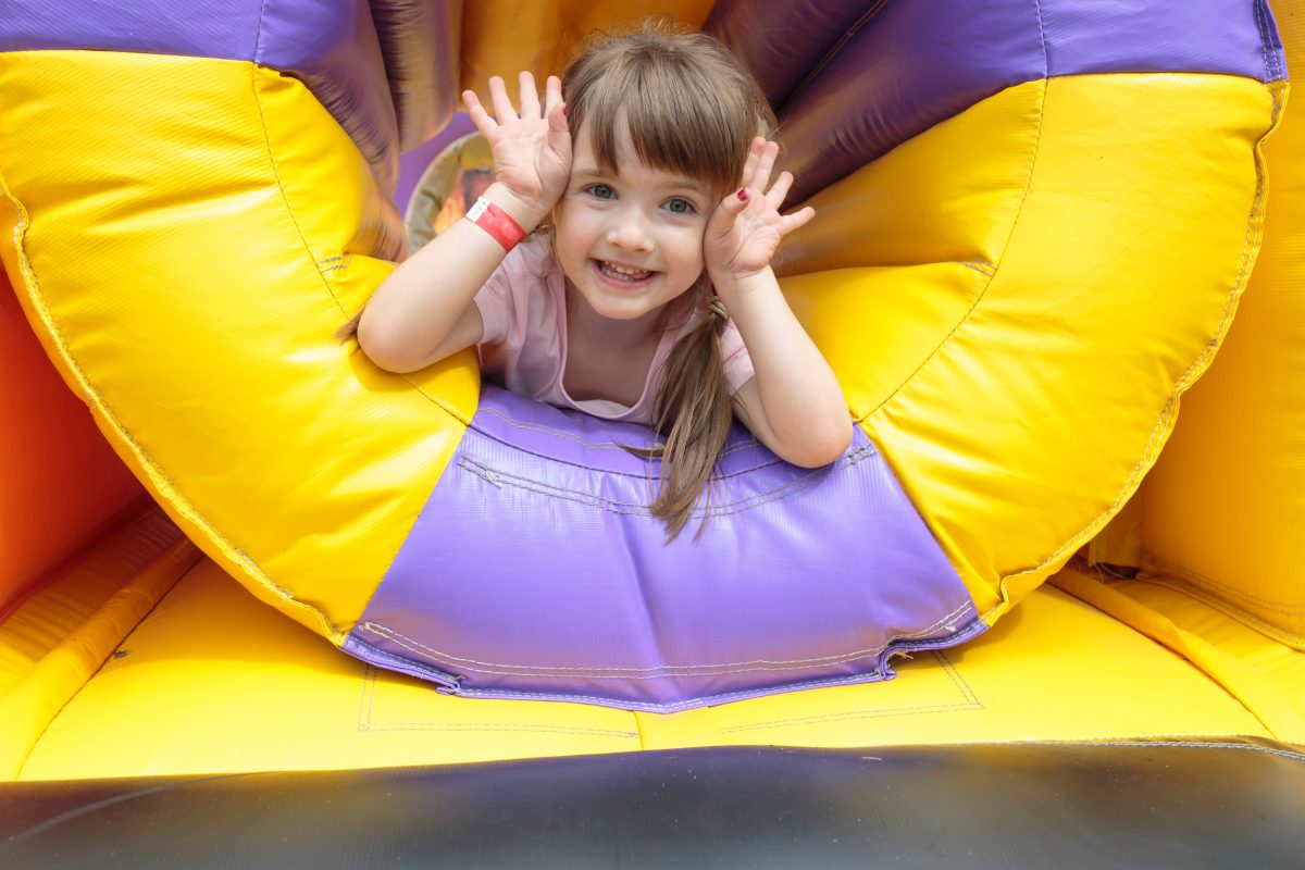 Prime bouncy castles for rent. Happy girl enjoying a bouncy slide with a big smile on her face.