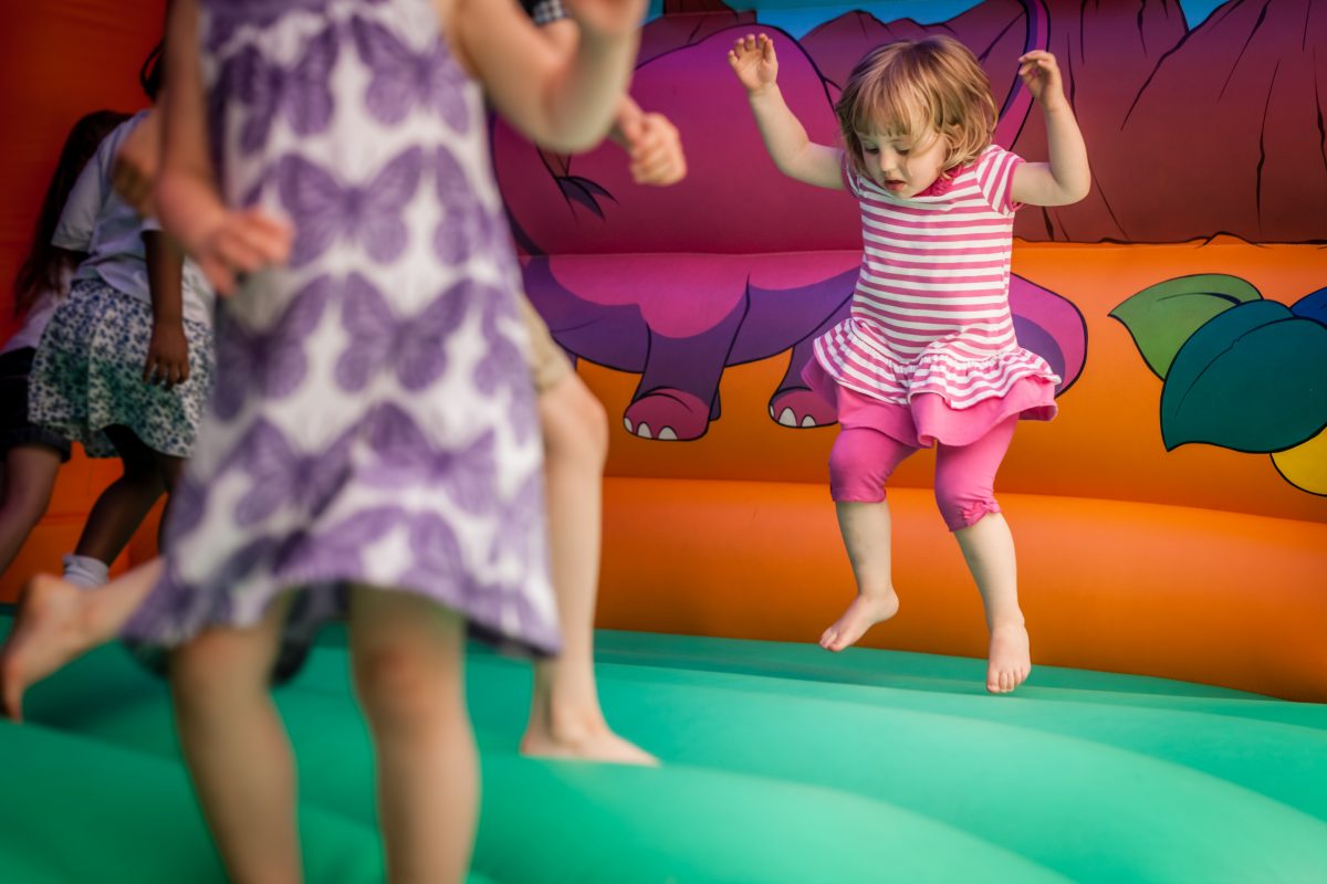 Prime bouncy castles for rent. Excited girl bouncing on a fun inflatable castle, enjoying a playful jump in the air.